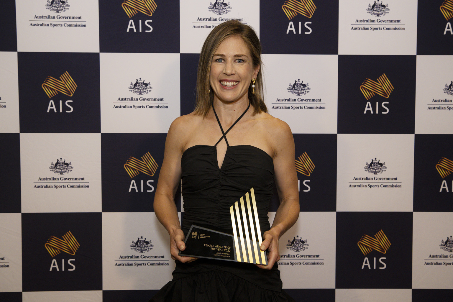 Jessica Stensen stands in front of an AIS and Australian Sports Commission banner with her ASPAs trophy