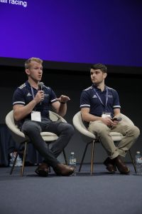 Two men sitting, one speaking into a microphone