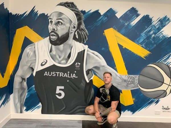 Artist Smalls alongside his Patty Mills artwork