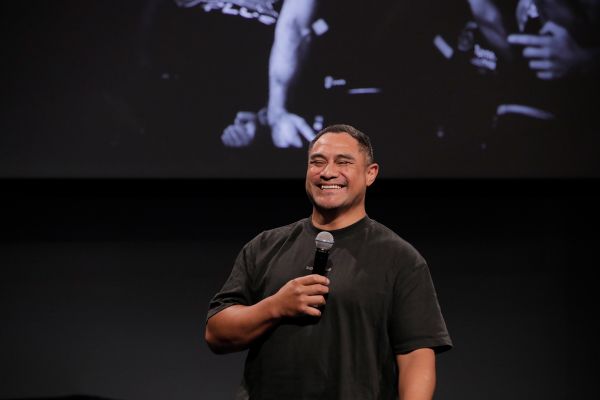 close up of a man holding a microphone grinning at the camera