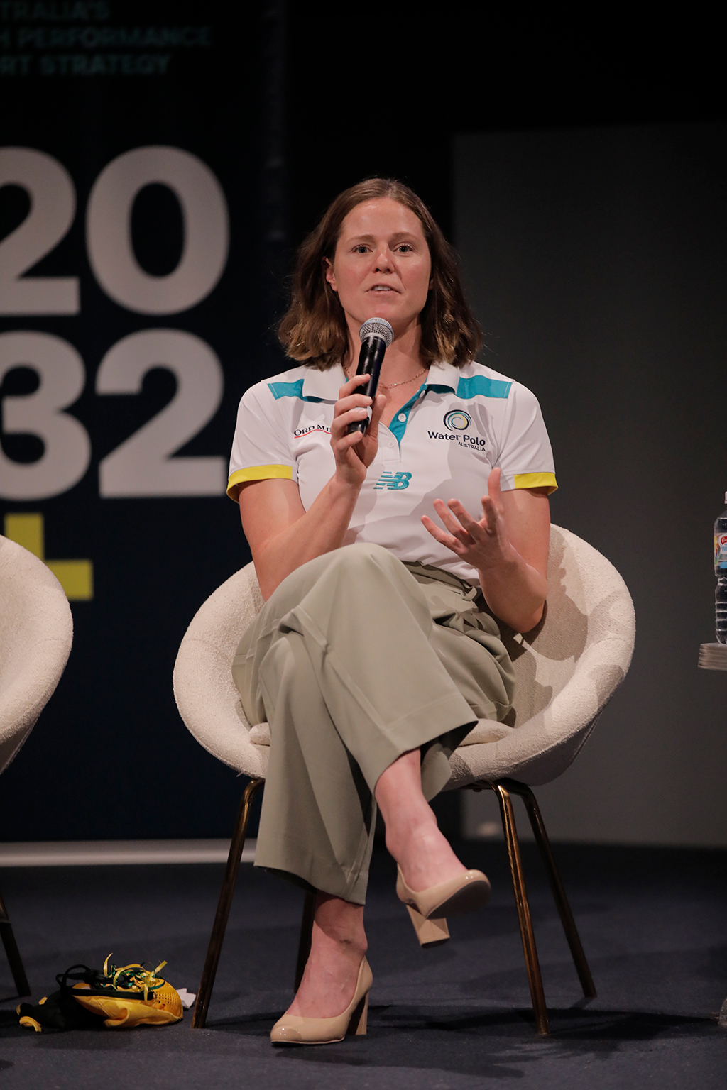 A woman wearing water polo australia shirt speaking into a microphone