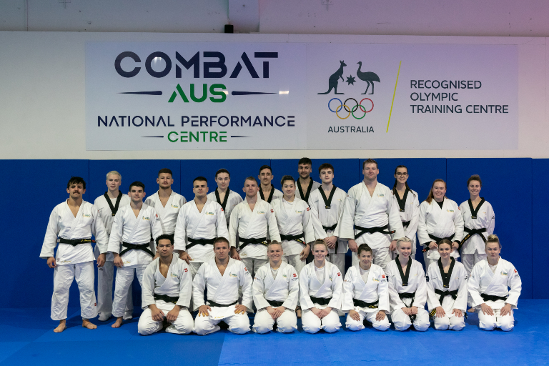 Athletes standing in front of National Performance Centre sign