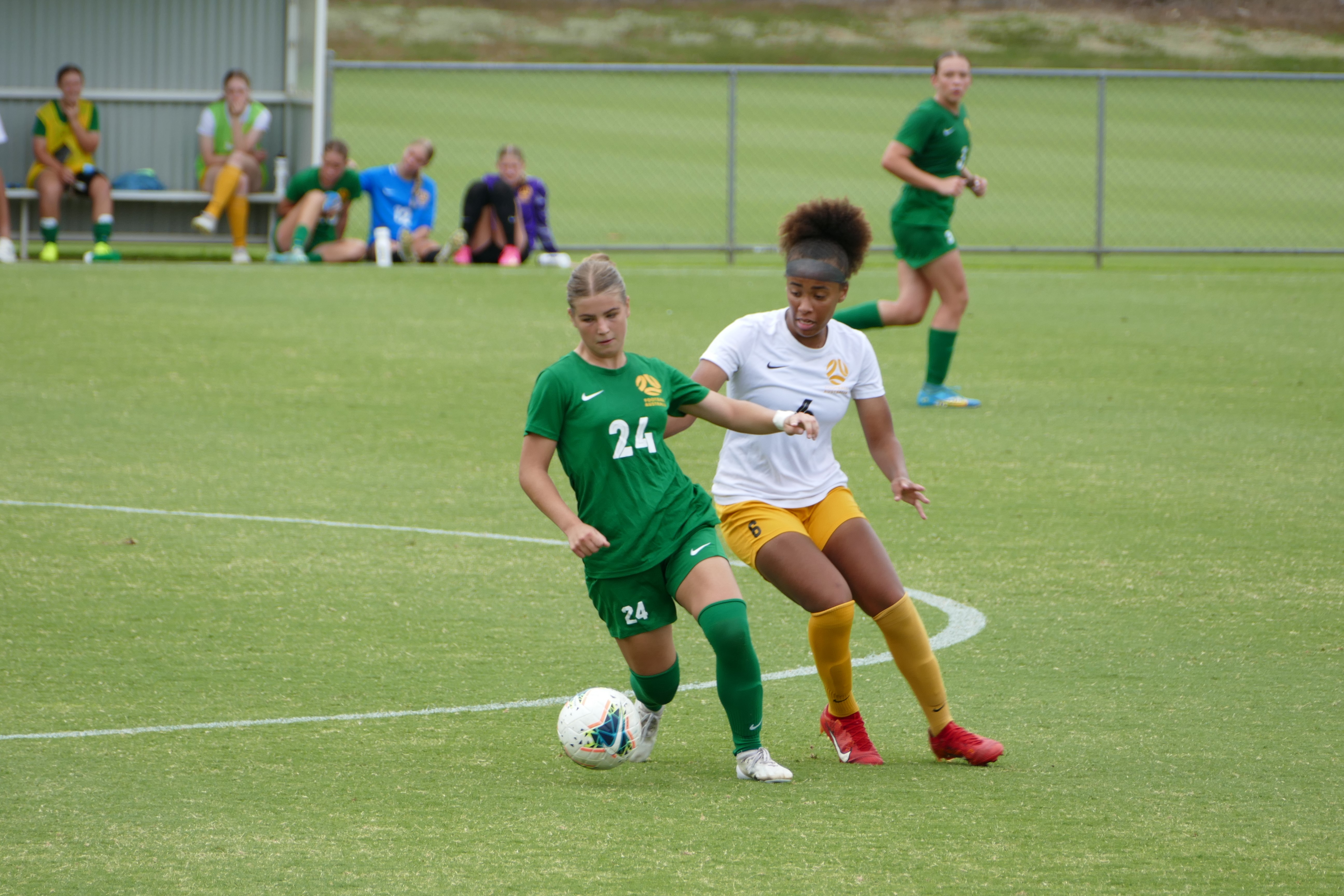 Two Junior Matildas players battling for the ball during a match