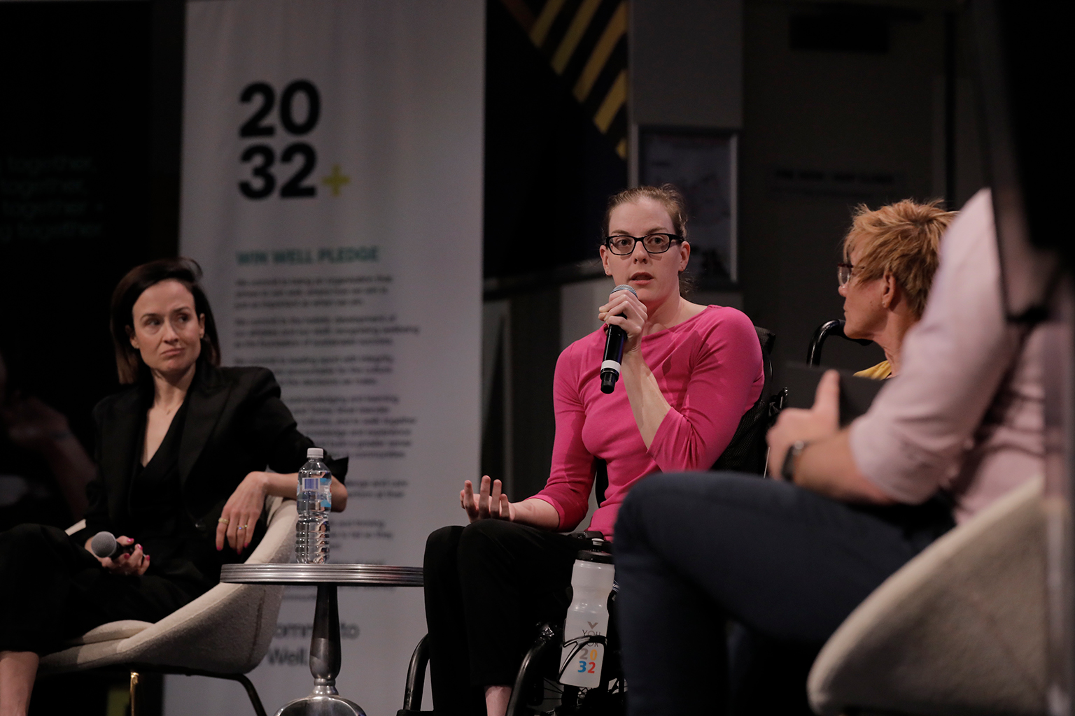 A woman in a wheelchair speaks into a microphone