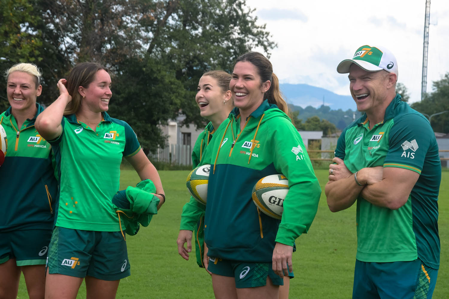 Aussy Rugby 7s players and coach stand together laughing