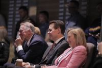 Three people seated together in an auditorium