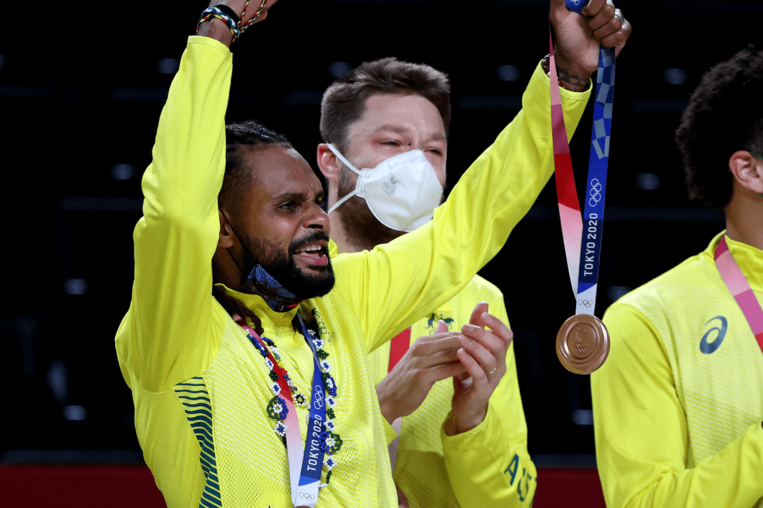Australian Boomers basketball team captain Patrick Mills holds up an Tokyo 2020 Olympic Bronze Medal, with Matthew Dellavedova in the background.