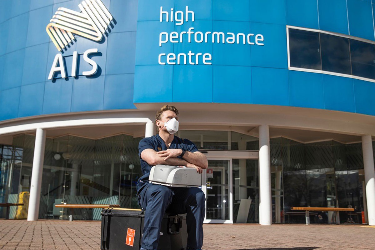 AIS PhD Scholar Dr Mat Mooney sits in front of the AIS building. 