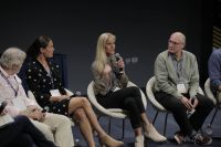 Four people sitting on stage, Nicole Hannan speaks into a microphone