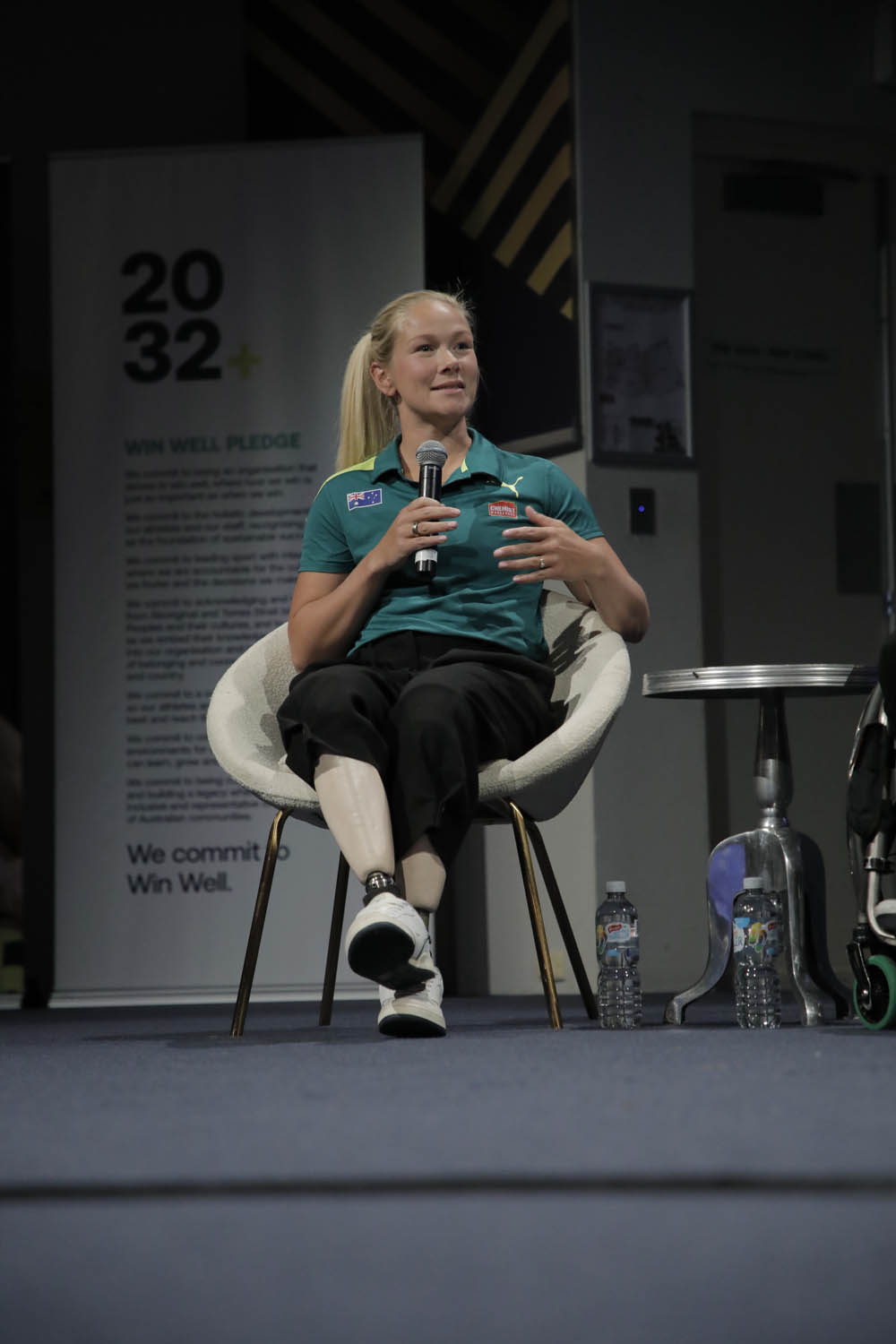 A woman with prosthetic legs speaks into a microphone