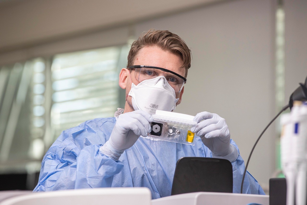 A man with a facemask in a lab holds up biofire technology