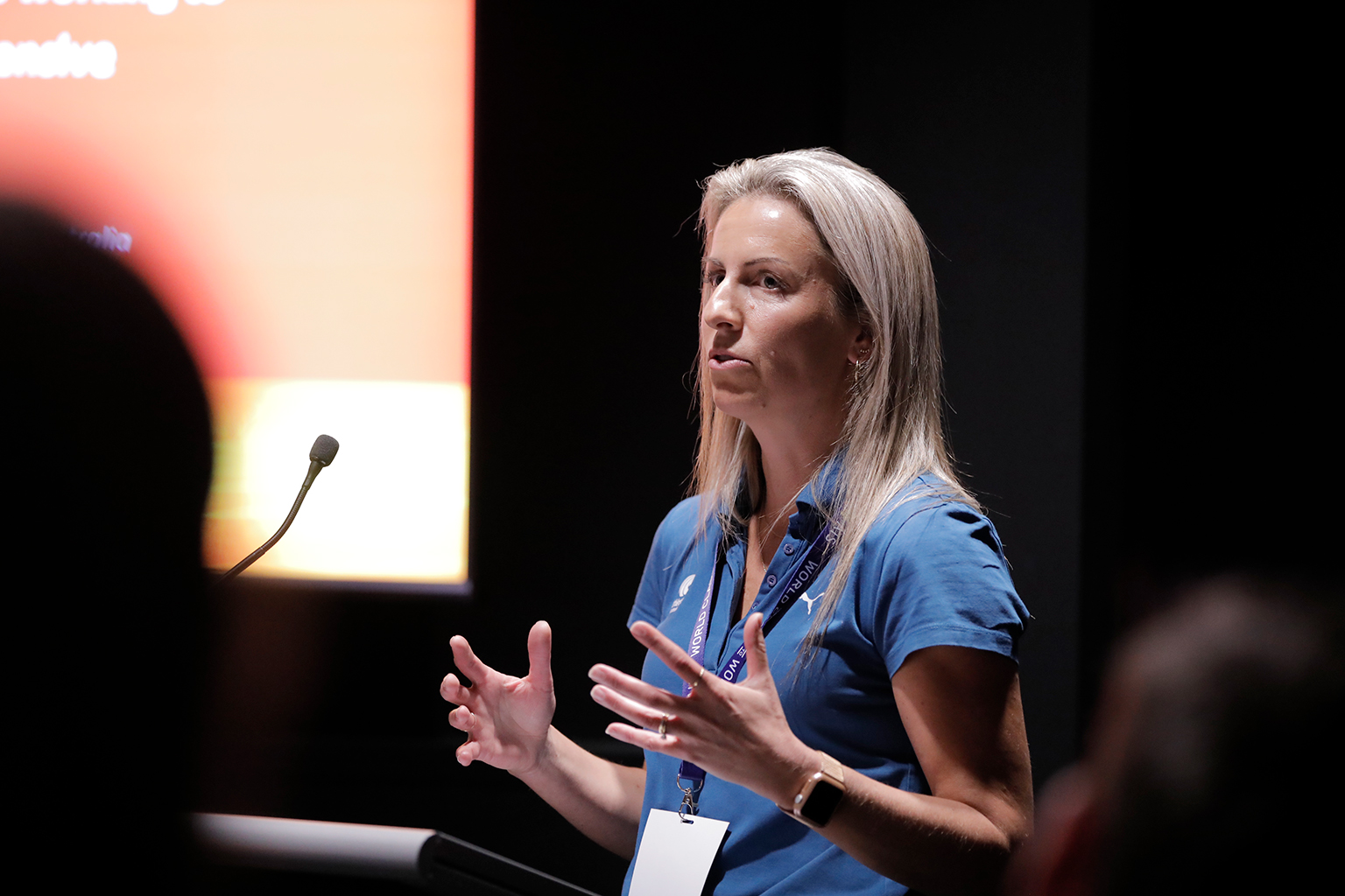 A woman behind a lectern in a dark room