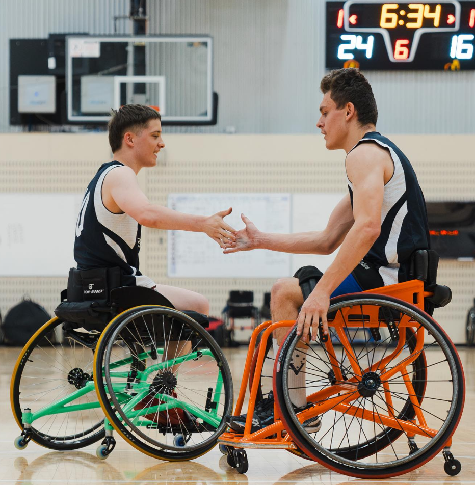 Wheelchair basketballers high five on court.