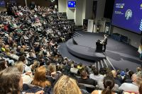 View across an auditorium with Kieren Perkins speaking on stage behind a lecturn