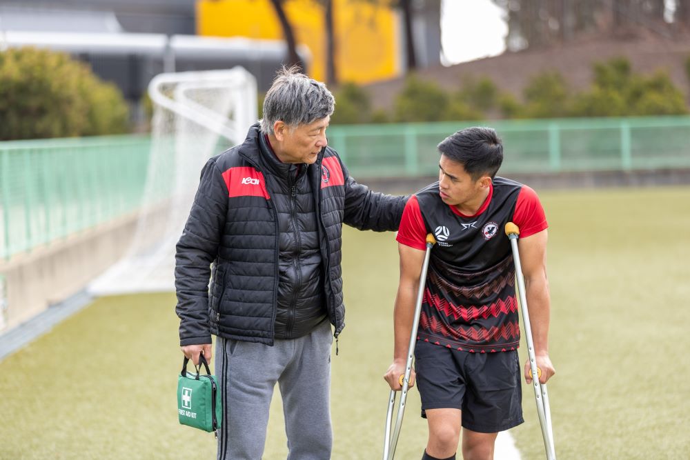 Coach assisting an athlete on crutches